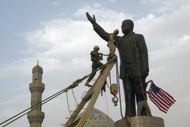 US Marines chain the head of a statue of Saddam Hussein before pulling it down in Baghdad's Firdous Square on April 9, 2003, while an Iraqi waves the US flag. US troops moved into the heart of the Iraqi capital meeting little resistance. AFP