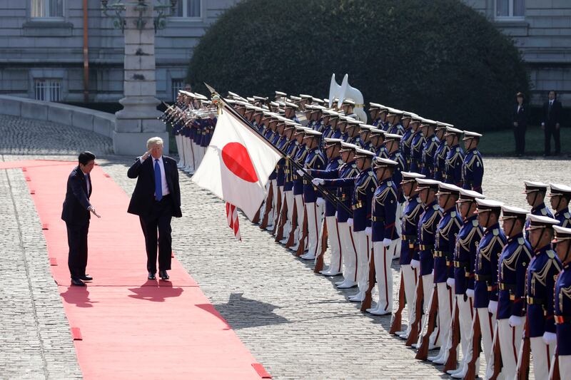 US president Donald Trump salutes as Japanese prime minister Shinzo Abe gestures while reviewing an honour guard at Akasaka Palace in Tokyo on Monday, November 6, 2017. Kiyoshi Ota / Pool Photo via AP