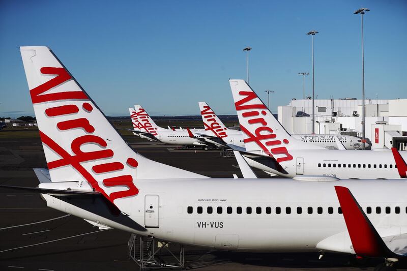 Aircraft operated by Virgin Australia Holdings Ltd. stand at Sydney Airport in Sydney, Australia, on Friday, August 17, 2020. Bain Capital’s resurrection of collapsed airline Virgin Australia Holdings Ltd. faces mounting legal opposition as bondholders rally to derail the takeover and salvage some of their debt. Photographer: Brendon Thorne/Bloomberg
