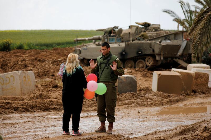 A woman gives balloons to an Israeli soldier near the border between Israel and Gaza on its Israeli side, March 15, 2019. Reuters