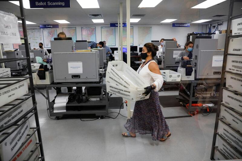 A worker of the Miami-Dade County Elections Department carries U.S. Postal Service trays with mail-in ballots in them in Miami, Florida. Reuters