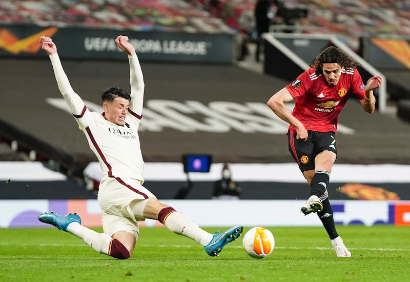 Manchester United's Edinson Cavani, right, kicks the ball during the Europa League semi final, first leg soccer match between Manchester United and Roma at Old Trafford in Manchester, England, Thursday, April 29, 2021. (AP Photo/Jon Super)