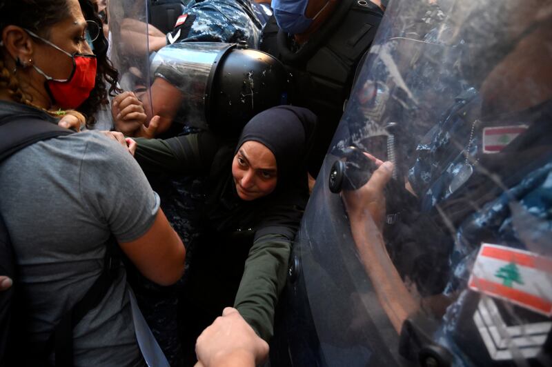Families and relatives of victims of the August Beirut port explosion clash with Lebanese riot police during a protest outside the Lebanese interior minister's house in Beirut.