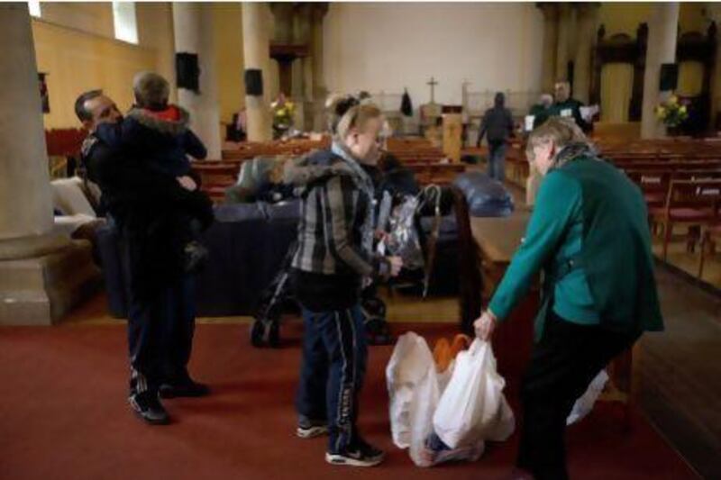 A volunteer, right, gives bags of groceries to a family at a food bank in St Luke's Church in West Norwood, London. More people are struggling to feed themselves as austerity measures hit the poor.