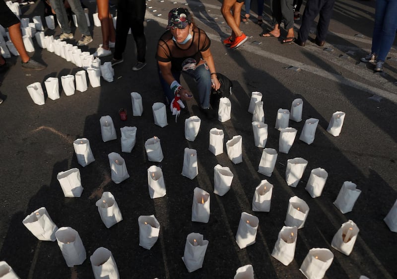 A demonstrator lights a candle during protests near the scene of a blast at Beirut's port area. Reuters
