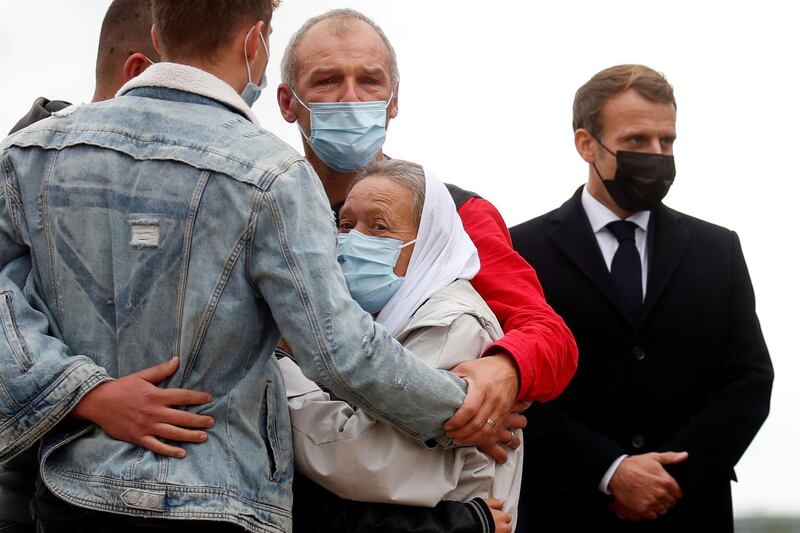 TOPSHOT - French President Emmanuel Macron (R) stands next to French aid worker Sophie Petronin (C) who is welcomed by her family after suspected jihadist hostage-takers freed the 75-year-old from nearly four years of captivity in Mali upon her arrival at the Villacoublay military airport near Paris on October 9, 2020. Petronin was released along with a top Malian politician and two Italian hostages late on October 8, 2020. The last French citizen known to have been held hostage anywhere in the world since her abduction in 2016, a white-robed Petronin was embraced by her son as she touched down in Mali's capital, Bamako.
 / AFP / POOL / GONZALO FUENTES
