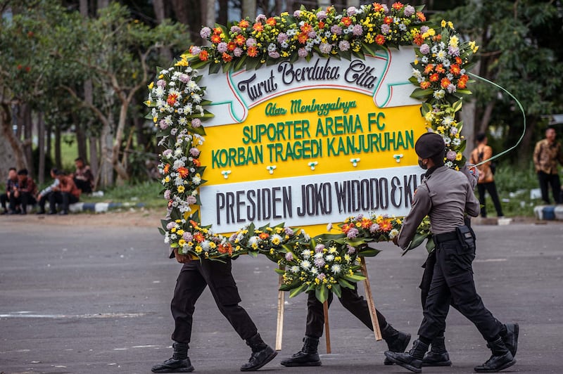 Police carry a wreath from Indonesia's President Joko Widodo at the Kanjuruhan stadium in Malang on October 5. AFP