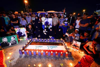 Iraqis commemorate fallen anti-government protesters by lighting candles around a national flag and praying, during the Muslim holy month of Ramadan in Iraq's central shrine city of Najaf, late on April 29, 2020.  / AFP / Haidar HAMDANI
