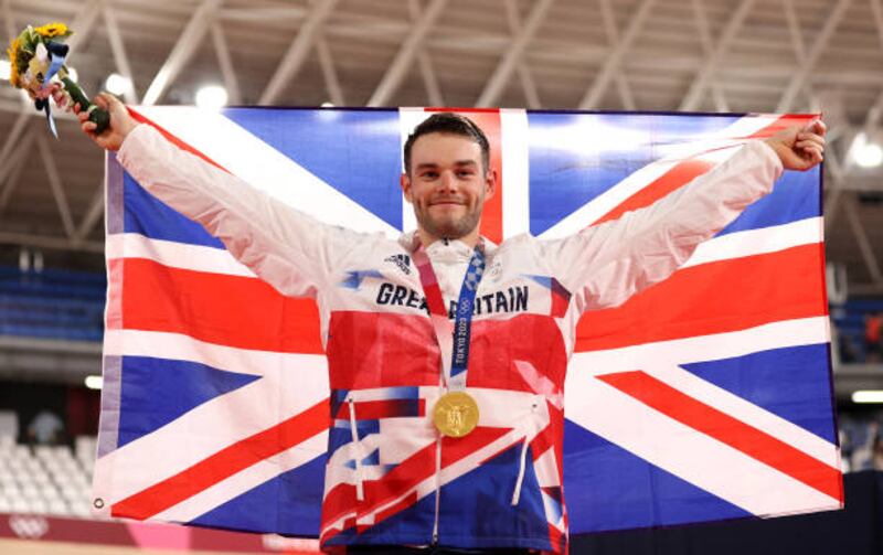 Gold medalist Matthew Walls of Team Great Britain poses while holding the flag of his country during the medal ceremony after the Men's Omnium points race.