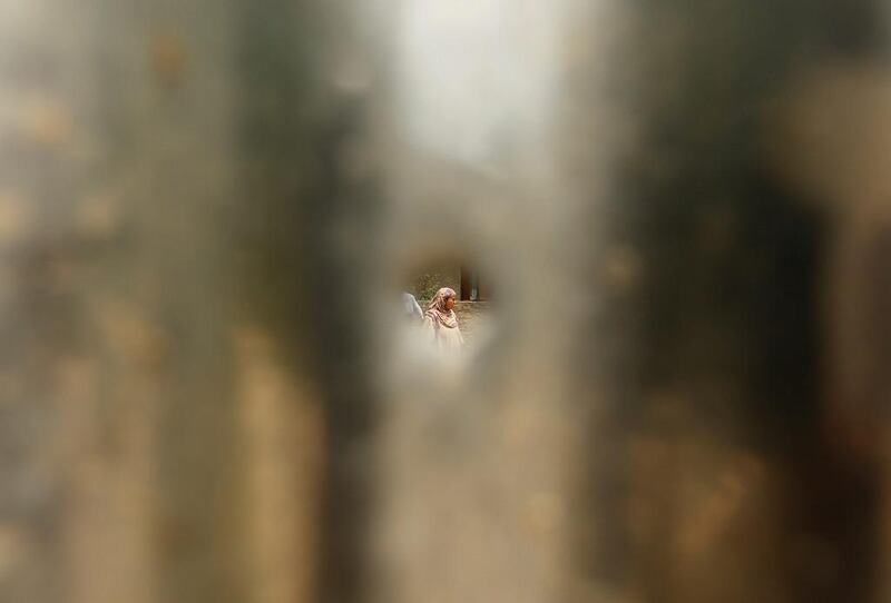 A woman is pictured through a bullet hole in a tin sheet in Lalhar, south of Srinagar.  Danish Ismail / Reuters