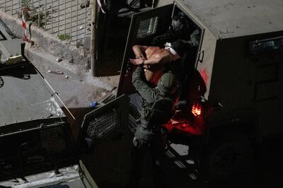 After being blindfolded, a Palestinian man is detained by Israeli forces during a raid in Jenin. AP