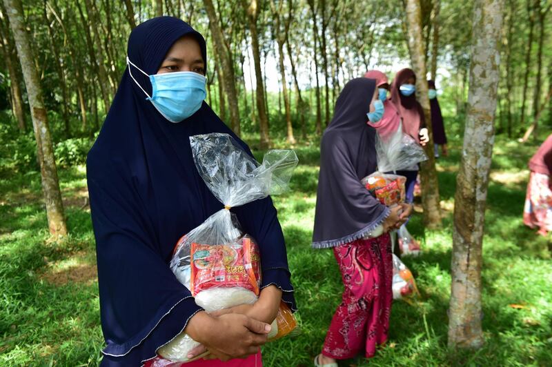 Muslim women wearing face masks amid concern over the spread of the COVID-19 coronavirus receive food aid donated by the Southern Peace Media Club in the southern Thai province of Narathiwat, ahead of Eid al-Fitr marking the end of the Islamic holy month of Ramadan.   AFP