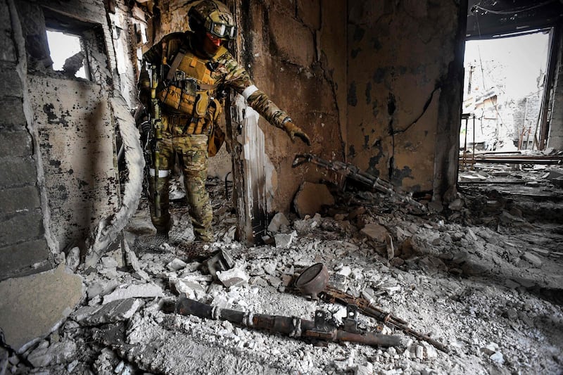 A Russian soldier collects weapons from inside the Mariupol drama theatre in Ukraine. AFP