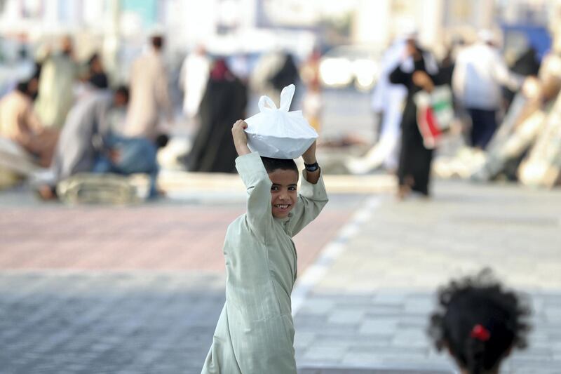 Abu Dhabi, United Arab Emirates - June 03, 2019: A boy carry sweets around on his head. People prepare for Eid. Monday the 3rd of June 2019. Bani Yas, Abu Dhabi. Chris Whiteoak / The National