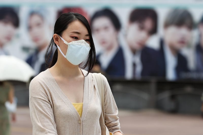 A woman wearing a protective mask crosses the road at Shibuya Crossing in Tokyo, Japan. Getty Images