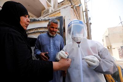 A healthcare worker takes blood samples from a woman during testing for the coronavirus disease (COVID-19) in Sadr city, district of Baghdad, Iraq May 21, 2020. REUTERS/Thaier Al-Sudani