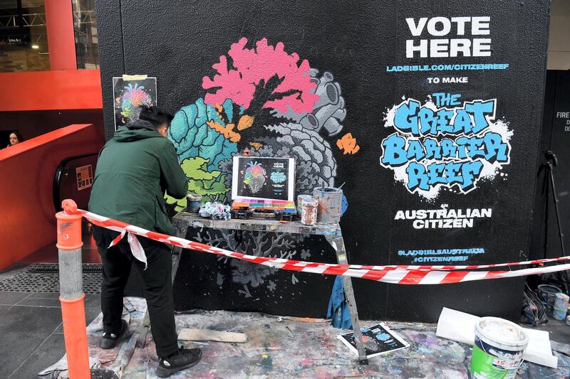 Artist Ed Wong paints a mural depicting coral in the shape of an anatomical heart with half of the heart deteriorating, representing the half of the Great Barrier Reef that has been bleached to death due to climate change, along a street in Melbourne on July 31, 2019. - Over 25,000 Australians have signed a petition to grant the Great Barrier Reef Australian citizenship in order to gain the reef the same rights and protections as all Australian citizens. (Photo by William WEST / AFP) / RESTRICTED TO EDITORIAL USE - MANDATORY MENTION OF THE ARTIST UPON PUBLICATION - TO ILLUSTRATE THE EVENT AS SPECIFIED IN THE CAPTION