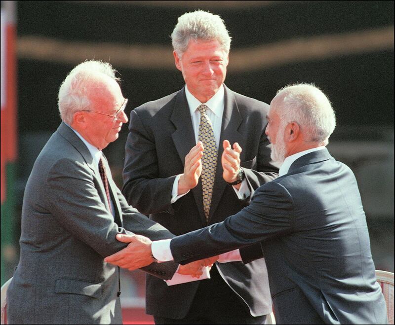 US President Bill Clinton (c) applauds as Jordan's King Hussein Ibn Talal (r) and Israeli Premier Yitzhak Rabin shake hands during the Israeli-Jordanian Peace Treaty signing ceremony at the Araba Israeli-Jordanian border 26 October 1994. (Photo by SVEN NACKSTRAND / AFP FILES / AFP)