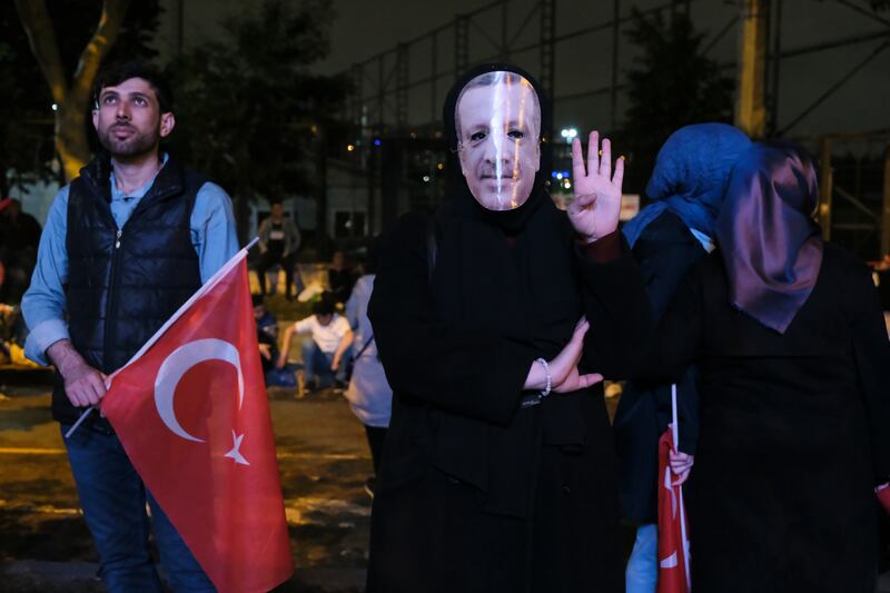 A woman wears a mask of Turkish President Recep Tayyip Erdogan while she watches his victory speech on a screen in Istanbul on Monday. Getty