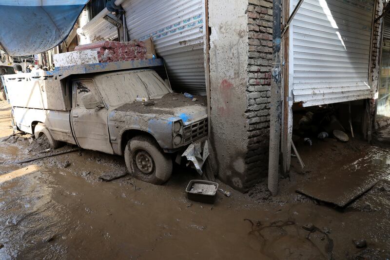 A vehicle and shop covered in mud after the flooding. AP Photo