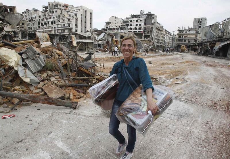 A woman carries items from her home following a ceasefire between rebels and forces loyal to Syria’s President Bashar Al Assad in Homs. Khaled Al Hariri / Reuters / May 9, 2014