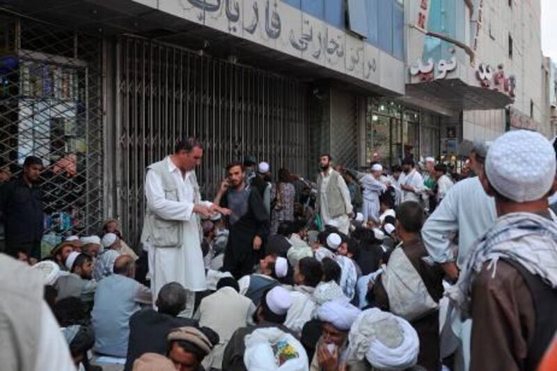 Men stand before the main branch of the Kabul Bank in Kabul on September 5, 2010. Branches of Afghanistan's biggest private bank were crowded with government employees queueing to be paid and customers wanting to withdraw their money following corruption allegations. Kabul Bank has been the subject of US newspaper reports alleging large-scale corruption by executives, though the government and central bank have said it is solvent and there is no need for customers to panic. AFP PHOTO/Massoud HOSSAINI