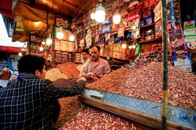 A dried fruit and nut merchant serves a client at a shop at an open-air market in Yemen's capital Sanaa on May 20, 2020, as Muslims shop ahead of the Eid al-Fitr holiday marking the end of the holy fasting month of Ramadan.  / AFP / Mohammed HUWAIS
