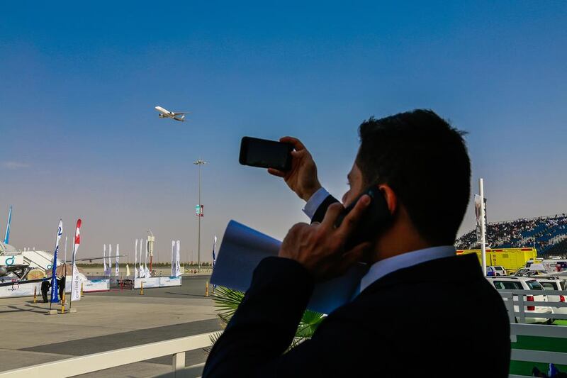 A visitor takes pictures as an aircraft flies past at the Dubai Airshow. Victor Besa for The National