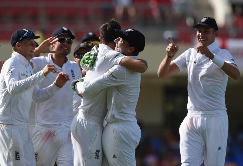 English fast bowler James Anderson (Centre L)c elebrates with teammates after becoming the highest ever English wicket taker with 384 after taking the wicket of West Indies captain Denesh Ramdin on day five of the first cricket Test match between West Indies and England at the Sir Vivian Richards Stadium in St John's, Antigua on April 17, 2015.  Anderson has taken the record from previous holder Ian Botham on 383.         AFP PHOTO/ MARK RALSTON (Photo by MARK RALSTON / AFP)
