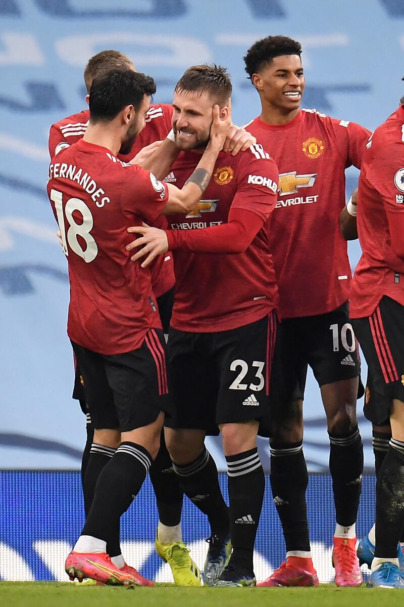 Manchester United's English defender Luke Shaw (C) celebrates scoring his team's second goal with Manchester United's Portuguese midfielder Bruno Fernandes (L) during the English Premier League football match between Manchester City and Manchester United at the Etihad Stadium in Manchester, north west England, on March 7, 2021. (Photo by PETER POWELL / POOL / AFP) / RESTRICTED TO EDITORIAL USE. No use with unauthorized audio, video, data, fixture lists, club/league logos or 'live' services. Online in-match use limited to 120 images. An additional 40 images may be used in extra time. No video emulation. Social media in-match use limited to 120 images. An additional 40 images may be used in extra time. No use in betting publications, games or single club/league/player publications. / 