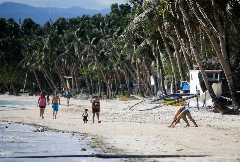 Tourists and resident walk along the almost empty beachfront as the government implements the temporary closure of the country's most famous beach resort island of Boracay. Aaron Favila / AP Photo