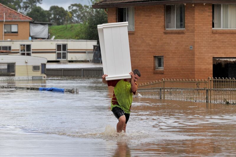 A resident moves furniture to a safer place from a flooded farm house in western Sydney. AFP