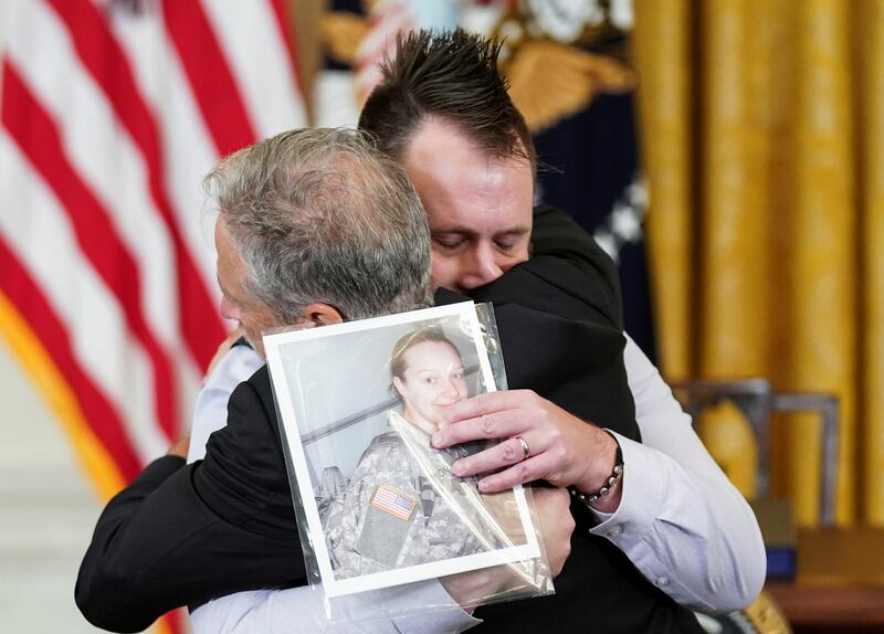 Stewart is embraced by Mr Benson, who holds a picture of his wife Katie. Reuters