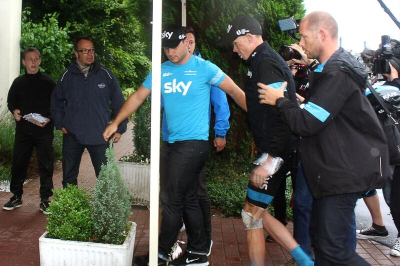 An injured Christopher Froome, centre, limps into his hotel after he abandoned the race on Wednesday. Jacques Radix / AFP