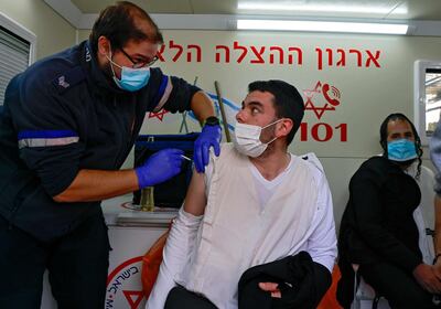 A paramedic administers a dose of the Pfizer/BioNTech coronavirus vaccine to an Israeli man inside a mobile clinic of Magen David Adom at the Mahane Yehuda Market in Jerusalem on February 22, 2021. Israel's inoculation campaign is regarded as the world's fastest, with one dose of the Pfizer/BioNTech vaccine administered to 4.25 million people out of its nine million-strong population since December, according to the latest health ministry figures. / AFP / MENAHEM KAHANA
