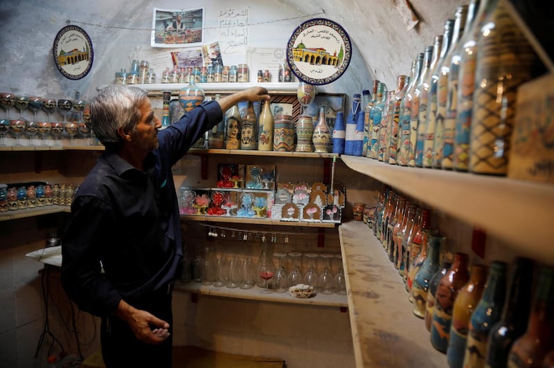 Al-Awawda arranges artworks at his shop. Reuters