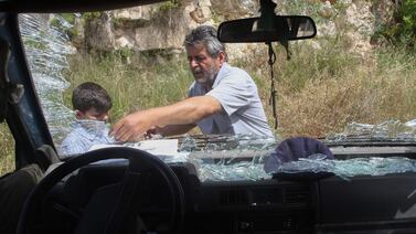 A Lebanese driver clears the glass of the smashed windshield of a school bus that was passing a car of a Hezbollah fighter which was trageted by an Israeli drone strike on a road leading to the southern Lebanese city of Nabatieh on May 23, 2024.  (Photo by Mahmoud ZAYYAT  /  AFP)