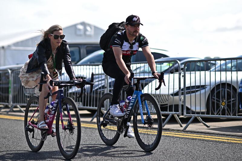 Alfa Romeo's Finnish driver Valtteri Bottas and his partner, cyclist Tiffany Cromwell, arrive on their bikes. AFP