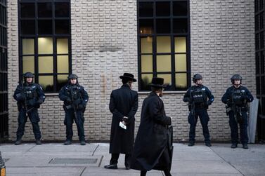 In this December 11, 2019 file photo, Orthodox Jewish men pass New York City police guarding a Brooklyn synagogue before the funeral of Mosche Deutsch in New York. Deutsch, a rabbinical student from Brooklyn, was killed during a shooting. AP