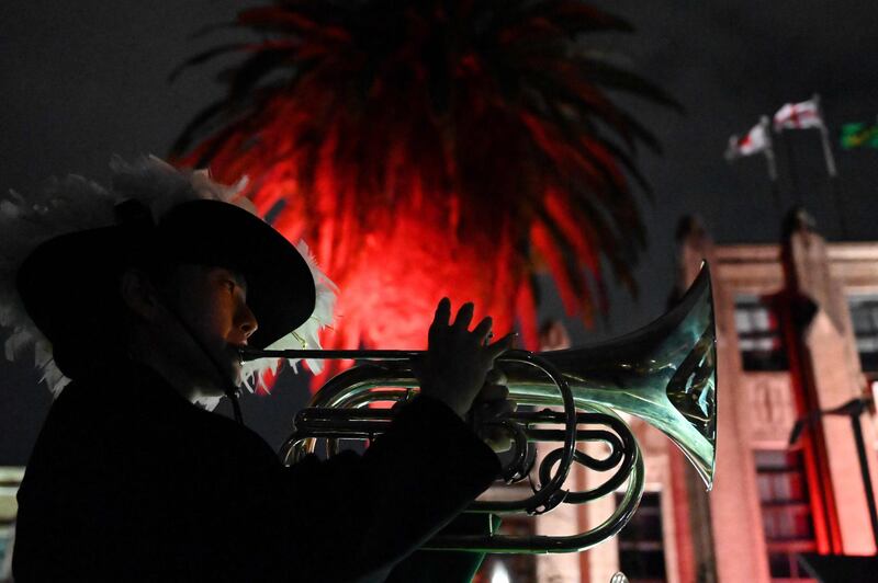 A member of a band performs in front of the official bus of England's rugby team. AFP