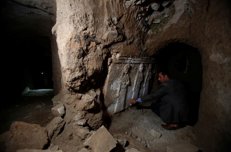Mr Jassim examines relief carvings found in tunnels beneath the mosque. Reuters