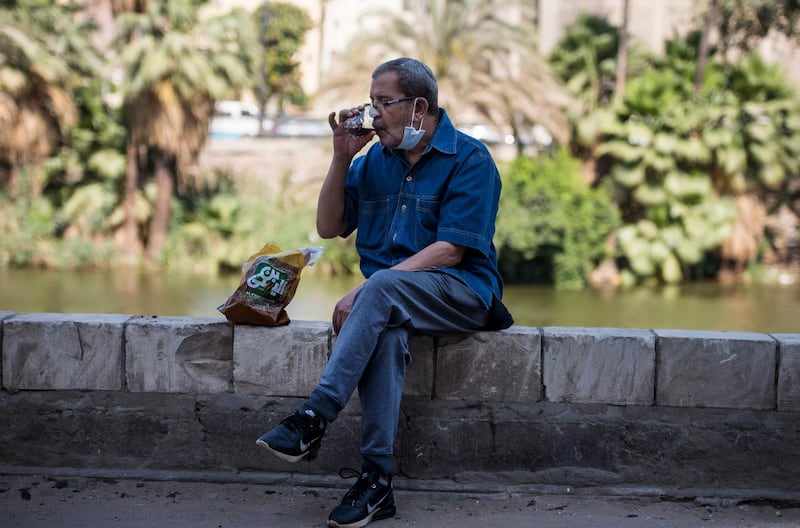 A man lowers his face mask as he drinks tea in Cairo, Egypt.  EPA