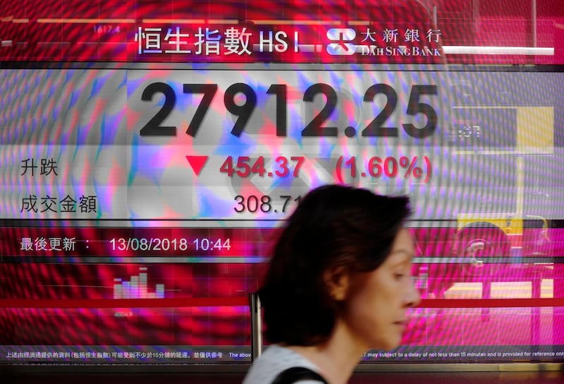 A woman walks past a bank electronic board showing the Hong Kong share index outside a Hong Kong local bank Monday, Aug. 13, 2018. Asian stock prices sank Monday as Turkeyâ€™s financial turmoil fueled fears contagion might spread to other emerging markets. (AP Photo/Vincent Yu)