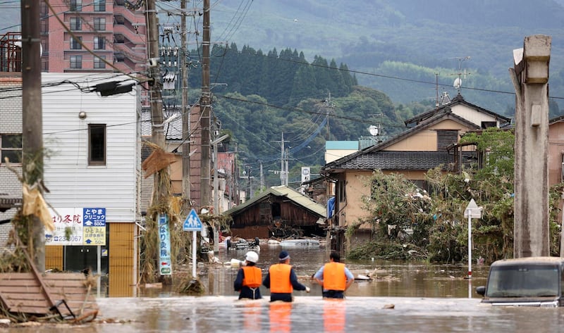 Police officers look for stranded people on a flooded street in Hitoyoshi, Kumamoto prefecture. Kyodo News via AP