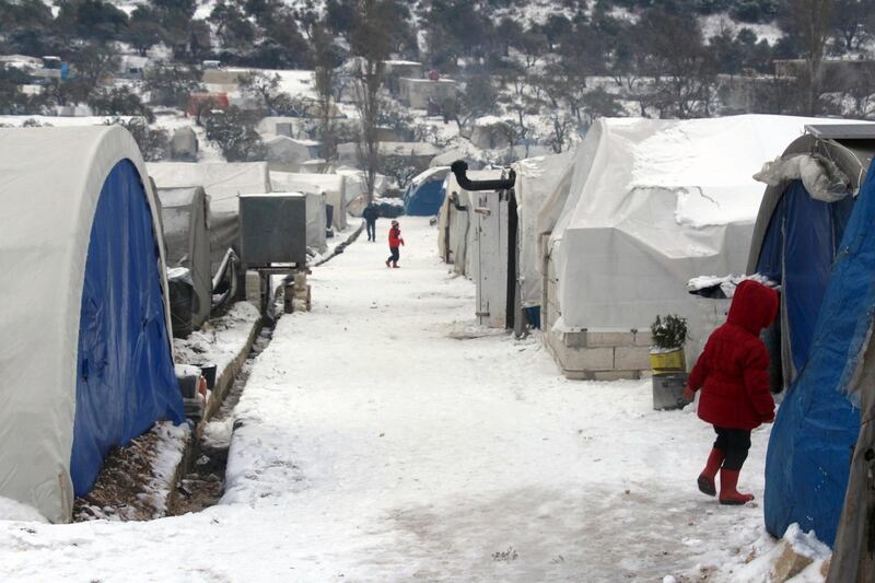 Syrian walking outside their tents at a displaced people camp near Turkish border, in Idlib province, Syria. AP