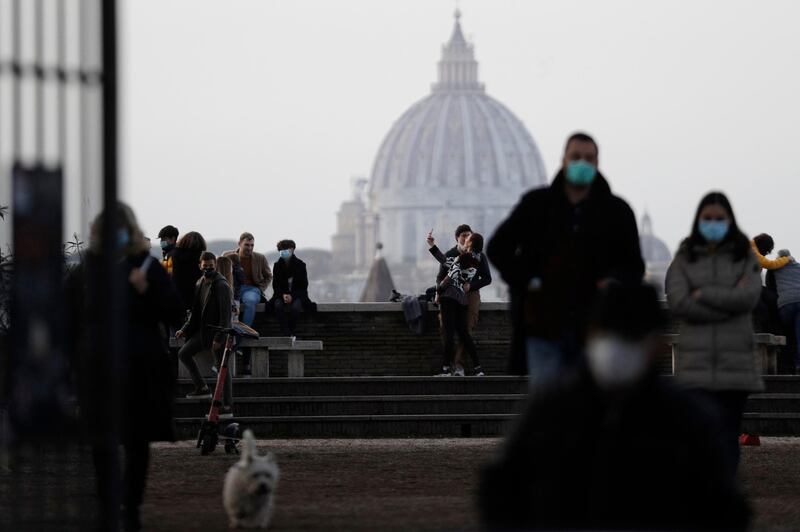 People gather on the terrace of the Giardino degli Aranci backdropped by the dome of St. Peter's Basilica, in Rome. AP Photo
