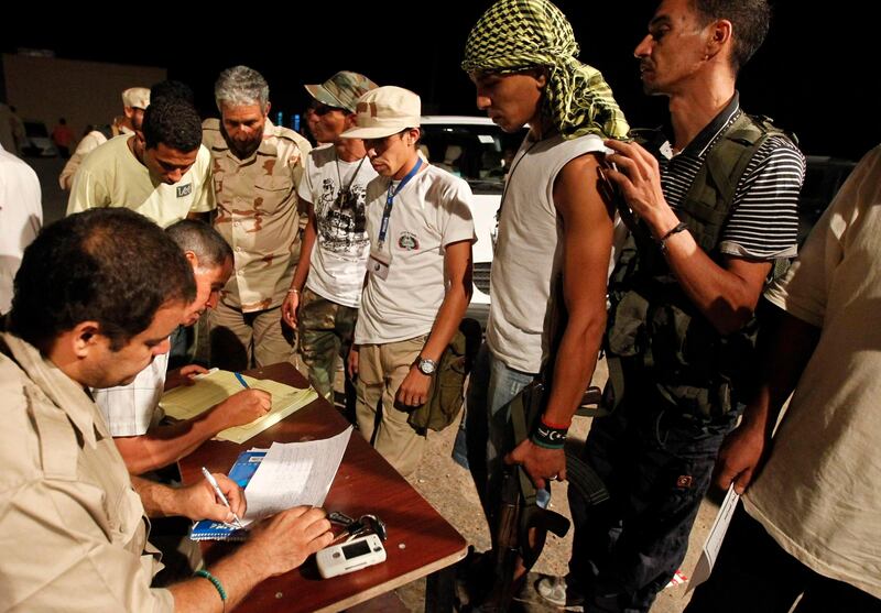 Men sign up as volunteers at a makeshift registry desk for anti-Gaddafi forces to fight on the frontline for the besieged city of Bani Walid as anti-Gaddafi forces step up fighting for control of one of Muammar Gaddafi's last remaining strongholds in Libya September 9, 2011. REUTERS/Zohra Bensemra (LIBYA - Tags: POLITICS CONFLICT) *** Local Caption ***  ZOH24_LIBYA-_0909_11.JPG