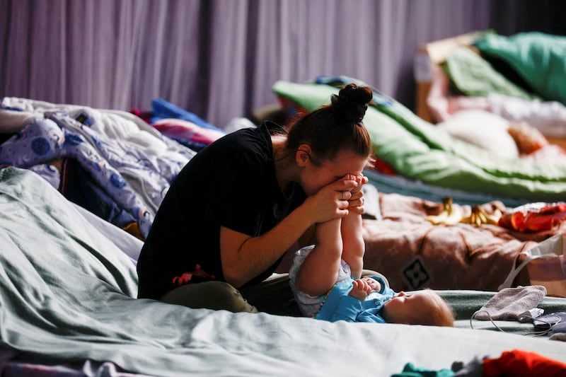 A Ukrainian woman plays with her child in a temporary refugee shelter in Przemysl, Poland. Reuters