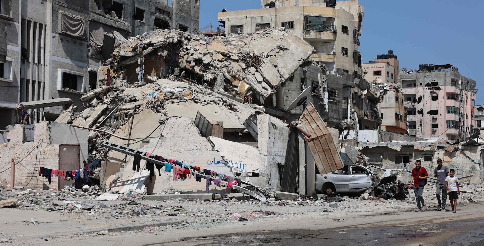 Palestinians walk a building destroyed by Israeli bombardment in Gaza City on May 3, 2024, amid the ongoing conflict between Israel and the militant group Hamas.  (Photo by AFP)