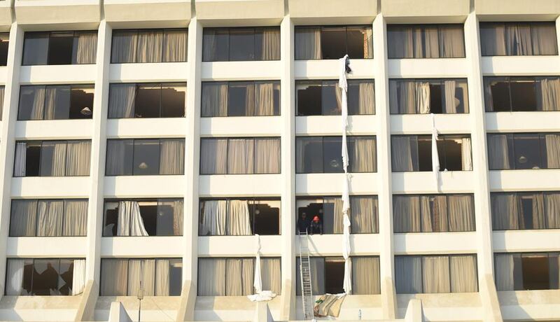 Pakistani fire fighters look from a room of Regent Plaza Hotel. At least two Pakistani international cricketers were staying at the hotel – Sohaib Maqsood and Hammad Azam – though they were not believed to be seriously injured. AFP